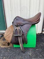 Left side view of saddle showing seat, flap, stirrup and leather