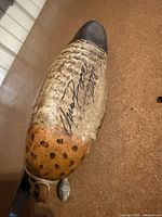 Underside of wooden duck decoy showing artist signature and lead weight