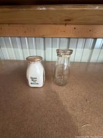Front view of both milk bottles showing River Crest Farms graphics and plain Diamond Dairy bottle