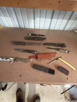 Overview of all knives, razor, sheaths and stones on tabletop