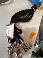 Black nylon cross tie coiled with attached nickel plated snaps and Weaver tag visible