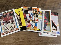 Stack of twenty Patrick Roy hockey cards fanned on wooden surface showing fronts and backs, visible Pro Set and All-Star designs