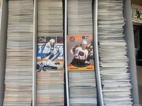 Three-row long cardboard box filled with thousands of Pro Set hockey cards, two sample cards (Mike Bullard, Brian Leetch) shown upright for reference