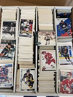 Three-row cardboard storage box filled with hockey trading cards from various brands and sets