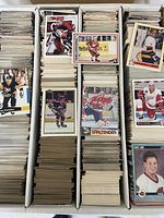 Three-row storage box filled with hundreds of hockey trading cards, several sample cards laid on top showing different sets