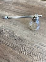 Side view showing glass reservoir and full metal nozzle arm