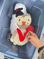 Hand-crocheted owl plush in bin alongside white plush background