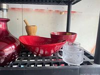Red bowls, wooden muddler, clear textured mugs, red vase visible