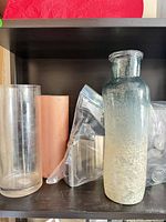 Group view of clear and copper-tone vases, bag with taco holders, ombré bottle vase