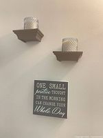 Overall view showing two wall shelves each holding a jar candle and decorative sign below