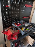 Full view of black metal shelving unit showing pegboard back, top shelf and attached red pegboard rails