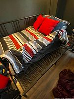 Overall view of black metal daybed frame with bedding showing upper frame structure