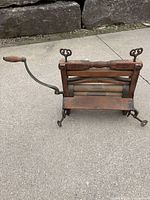 Front view showing wood frame, rollers, crank handle, clamp feet