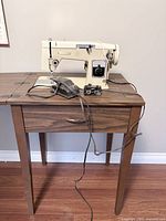 Sewing machine on table with foot pedal and control unit visible