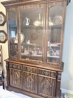 Full view of dark brown wood china cabinet hutch with glass doors and lower storage