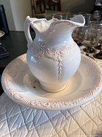white porcelain pitcher and wash basin with pink accents on quilted surface