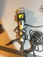 Single MTV microphone with black/yellow logo flag showing attached cable and 1/4-inch jack