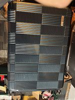 Front view of hardside suitcase showing grid pattern shell and spinner wheels