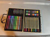 Open Colorama art kit showing markers, oil pastels, colored pencils and watercolor paints neatly arranged