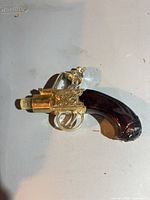 Left side view of Avon flintlock pistol decanter showing brown glass grip and gold-tone plastic barrel and action