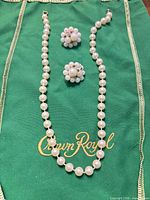 Necklace and earrings laid out on green cloth