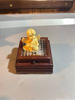 Full view of cherub seated on wood music box with grid top