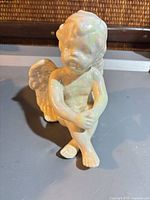 Front view of seated iridescent porcelain cherub