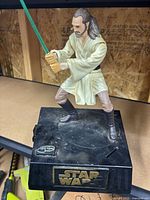 Front view of Qui-Gon Jinn figure on coin bank base