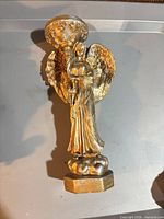 Front view of gold-tone angel candle holder showing candle cup and base