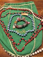 All four bead necklaces and stretch bracelet laid out on green background