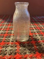 Front view of clear glass milk bottle standing upright