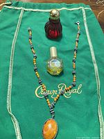 Overall lot showing necklace and two perfume bottles on green cloth
