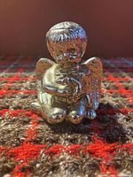 Front view of silver-plated kneeling cherub figurine holding bird
