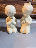Front view of both kneeling praying child figurines