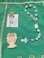 Overview of pin on card, resin angel figurine, and one-decade rosary