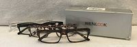 Four pairs of reading glasses in front of Wenlook box