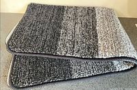 Folded bath mat showing gradient stripes and edging