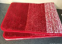Two stacked red and white bath mats showing top surface