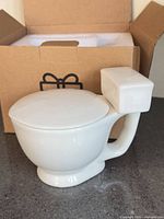 White ceramic toilet-shaped mug outside box