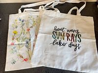 Both tote bags laid flat showing designs