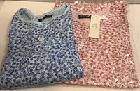 Blue and pink folded nightgowns showing floral prints and tags