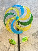 Front view of metal flower spinner garden stake showing multicolour pinwheel head, centre hub, stake and leaves