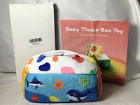 Front view of tissue box toy, instruction leaflet and barcode card