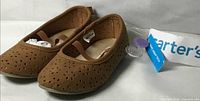 Three-quarter view of both shoes showing perforated uppers, elastic strap and tag