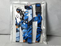 Front of sealed package showing blue patterned harness and leash