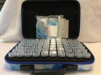 Open carrying case showing 60 organizer cups in foam insert and diamond art tools in mesh pocket