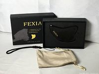 Box, gua sha tool in foam insert, pouch and strap displayed