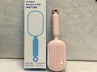 Front view of pink air-bag paddle hairbrush beside its retail box