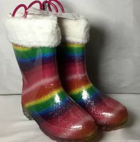 Front view of both boots showing rainbow glitter pattern, fur cuff and light-up sole
