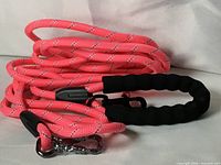 Coiled neon pink reflective rope leash with black padded handle and metal hook
